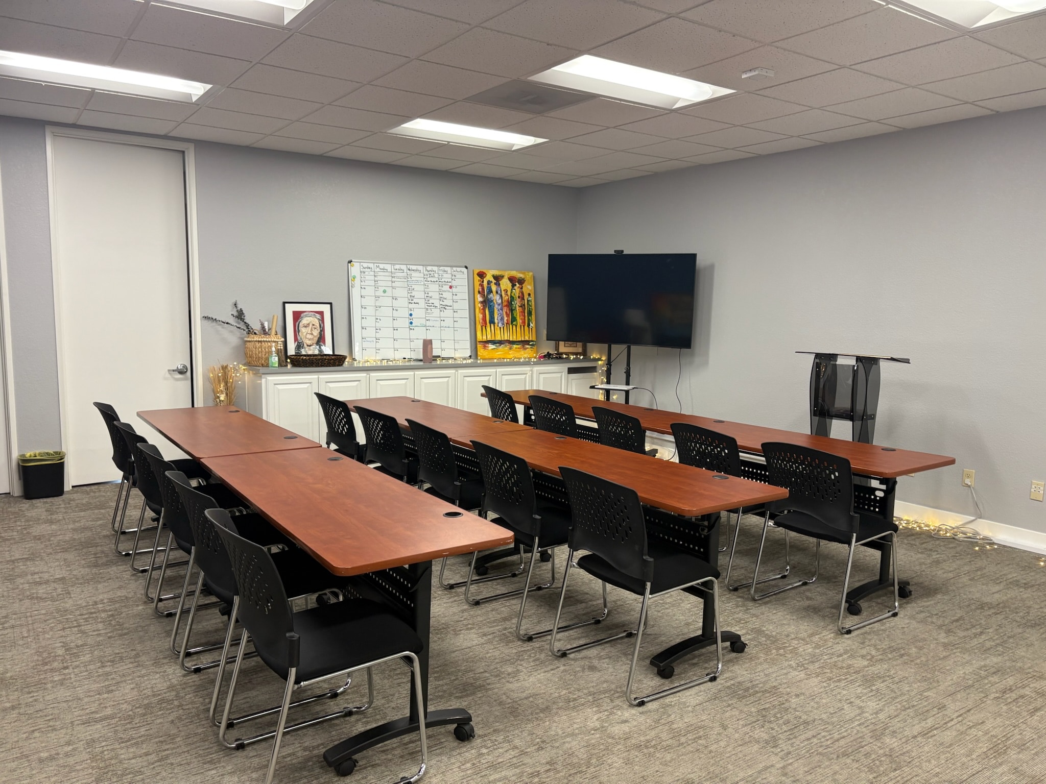Suite 700 conference room with long rows of tables, whiteboard, and colorful artwork — Sacramento meeting room rental