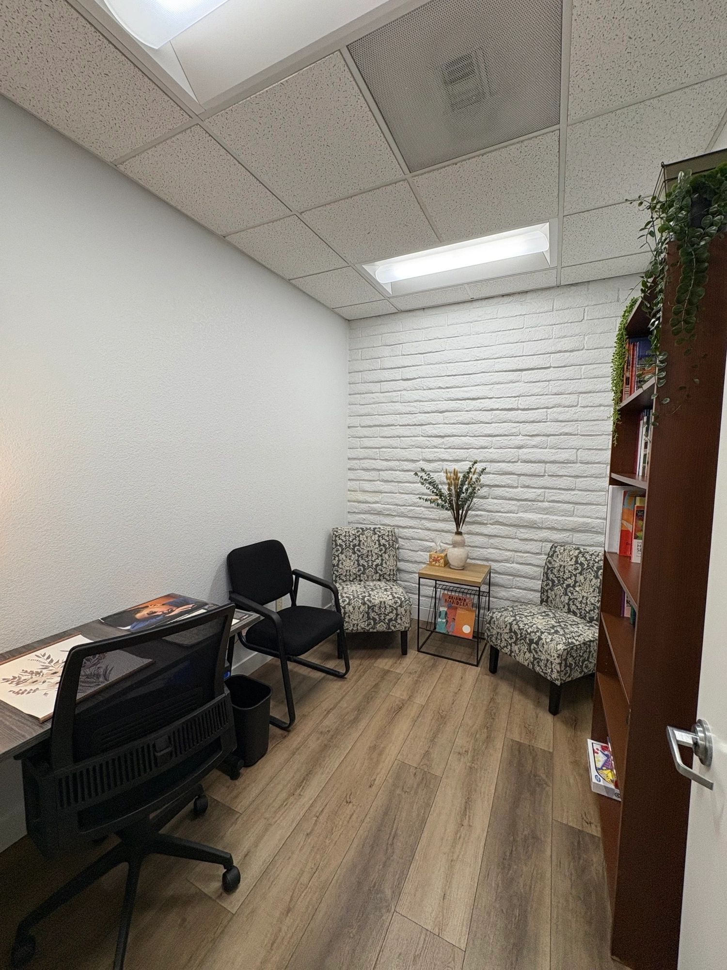 Private consultation office with armchairs and white brick wall — hourly office rental Sacramento
